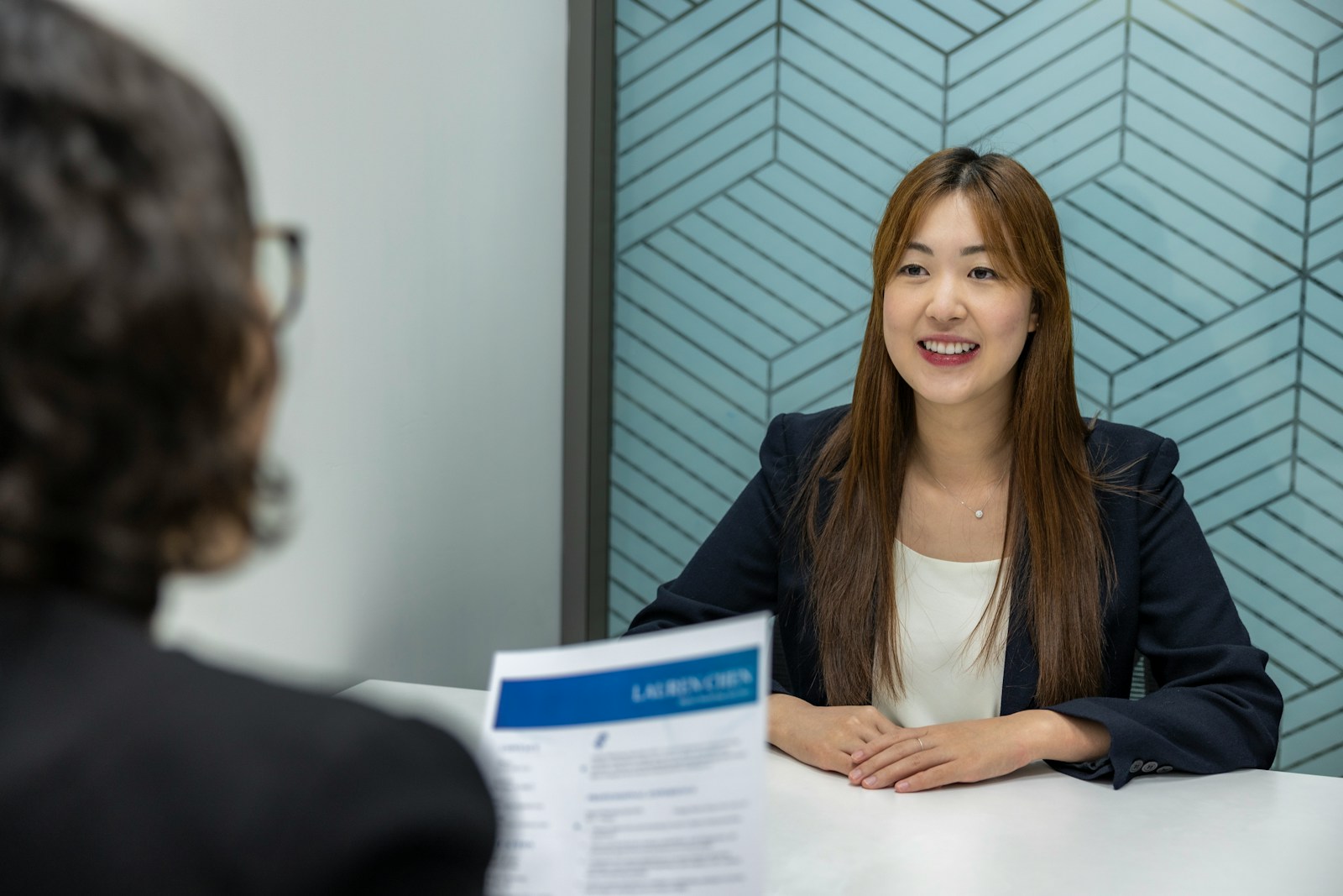 a woman sitting at a table with a piece of paper in front of her, business